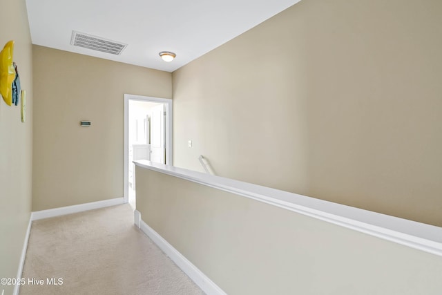 hallway featuring visible vents, light carpet, baseboards, and an upstairs landing