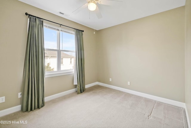 spare room featuring visible vents, light colored carpet, baseboards, and a ceiling fan