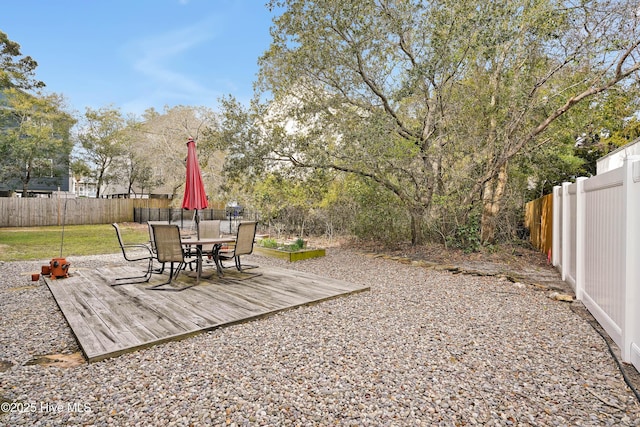 view of yard featuring a deck, a fenced backyard, and outdoor dining space