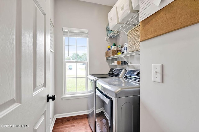 clothes washing area featuring baseboards, wood finished floors, laundry area, and washer and clothes dryer