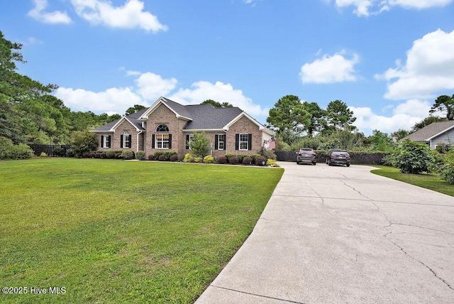 view of front of house with concrete driveway, fence, brick siding, and a front yard