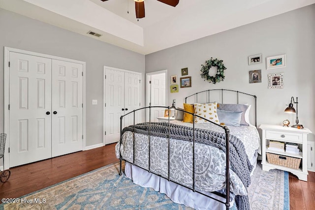 bedroom with visible vents, multiple closets, baseboards, and wood finished floors