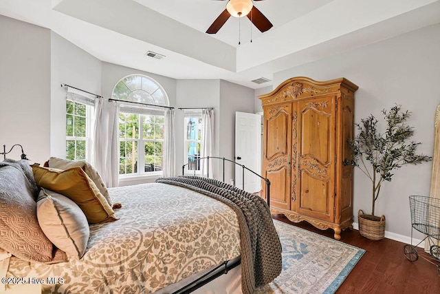 bedroom with dark wood finished floors, visible vents, a ceiling fan, and baseboards