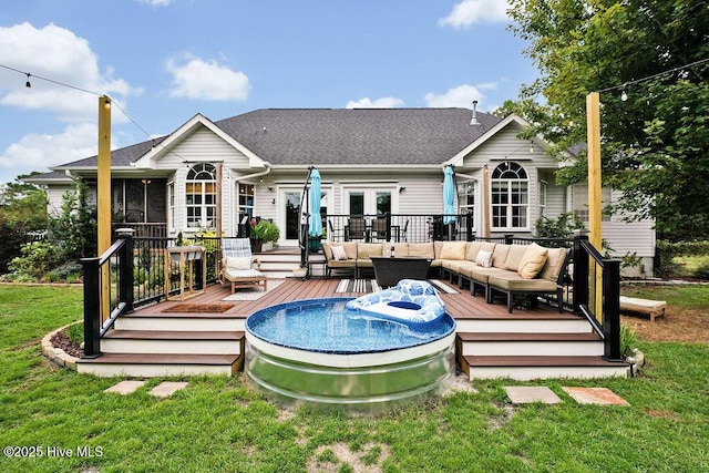 rear view of house with a lawn, french doors, roof with shingles, a wooden deck, and an outdoor hangout area