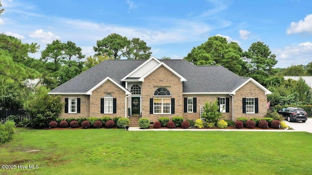 view of front of property with brick siding, roof with shingles, and a front lawn