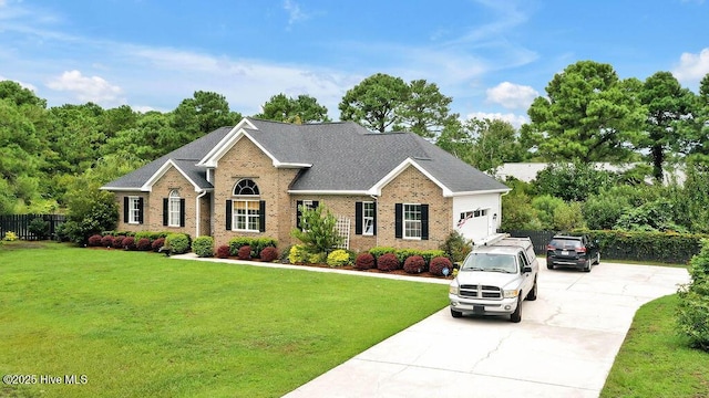 view of front facade featuring brick siding, concrete driveway, a front yard, and fence