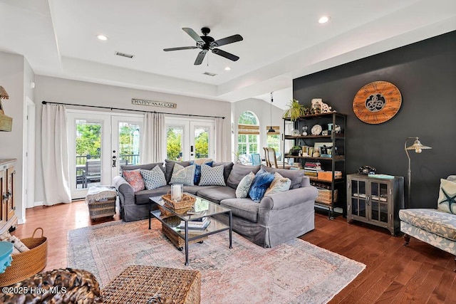 living room featuring a wealth of natural light, visible vents, wood finished floors, and french doors