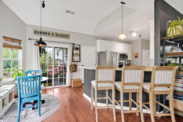 kitchen featuring visible vents, decorative light fixtures, lofted ceiling, hardwood / wood-style floors, and stainless steel appliances