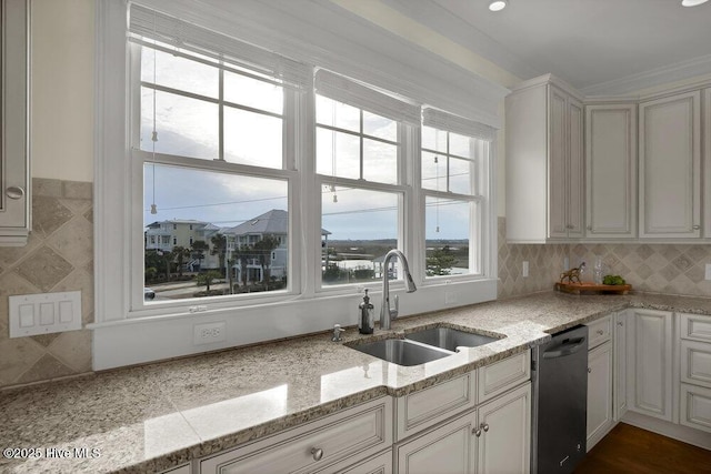 kitchen featuring a sink, light stone counters, backsplash, and dishwasher