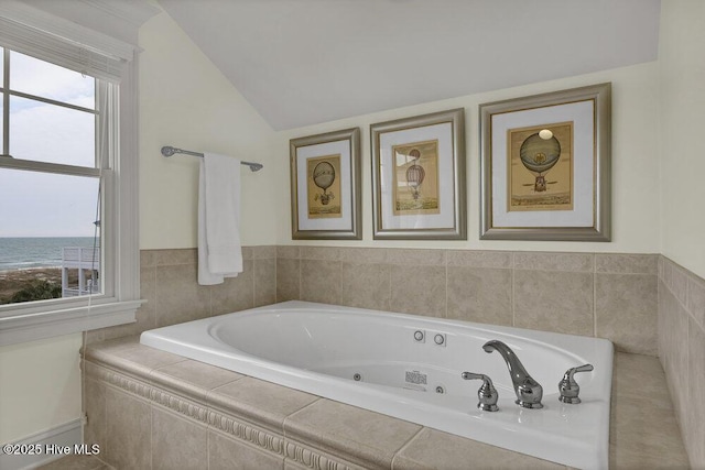 bathroom with lofted ceiling, a tub with jets, and a water view