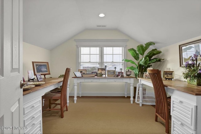 office area with built in desk, light colored carpet, visible vents, and vaulted ceiling