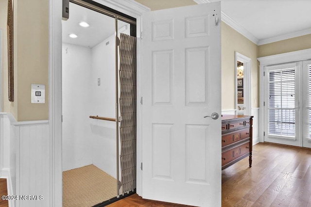 bathroom featuring elevator, wood finished floors, wainscoting, and crown molding