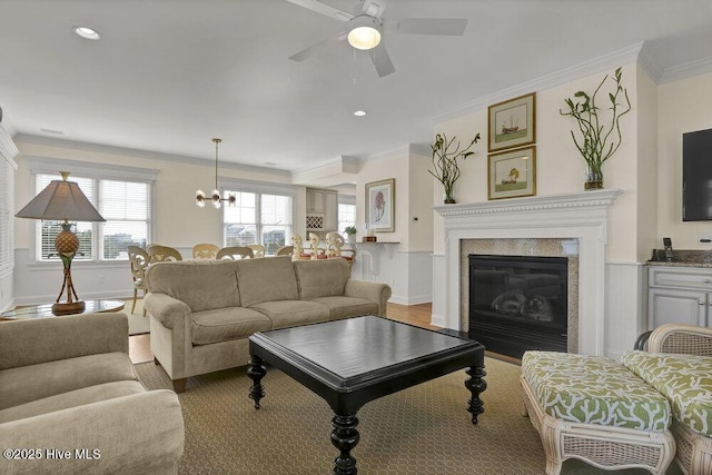 living area featuring a glass covered fireplace, baseboards, light wood-style floors, and ornamental molding