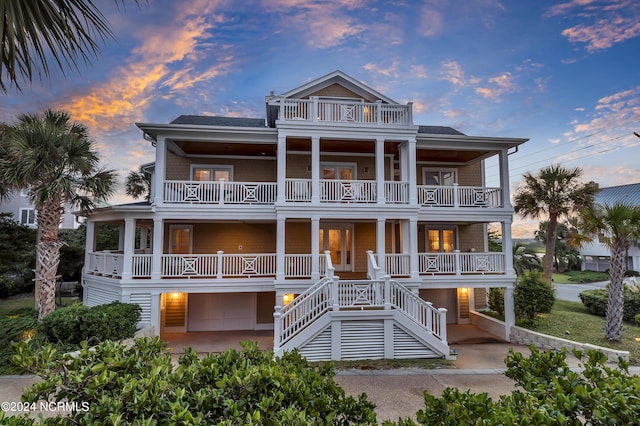 beach home featuring stairway, a balcony, covered porch, and an attached garage