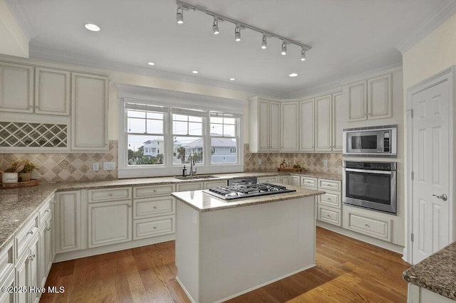 kitchen featuring appliances with stainless steel finishes, wood finished floors, crown molding, and a sink