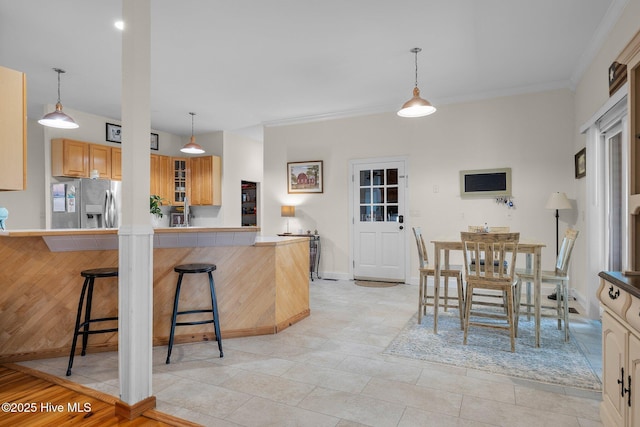 kitchen with a kitchen breakfast bar, stainless steel fridge, a peninsula, and hanging light fixtures