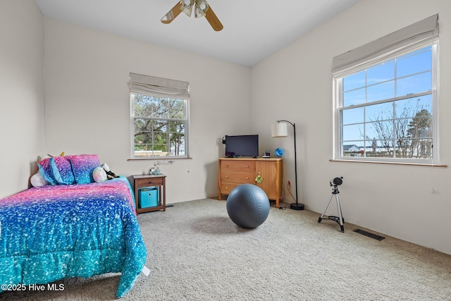 carpeted bedroom featuring a ceiling fan and visible vents