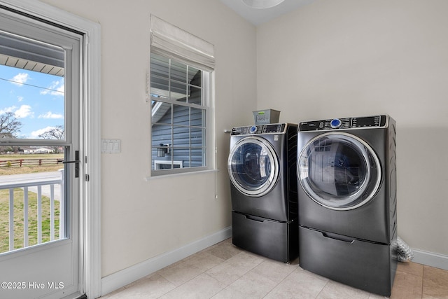 washroom with laundry area, light tile patterned floors, separate washer and dryer, and baseboards