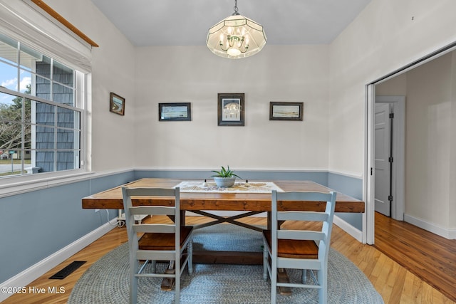 dining area featuring baseboards, wood finished floors, visible vents, and a chandelier