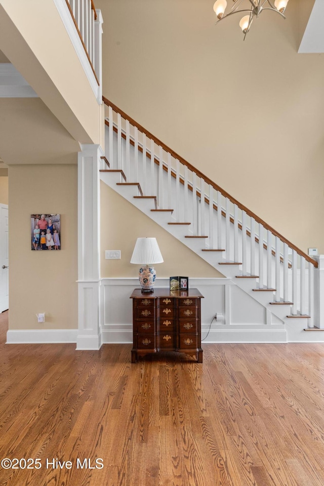 8904 Sound View Ct, Emerald Isle, NC 28594 - stairway with a wainscoted wall, wood finished floors, a notable chandelier, and a decorative wall