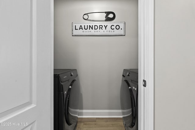 laundry room with baseboards, separate washer and dryer, wood finished floors, and laundry area