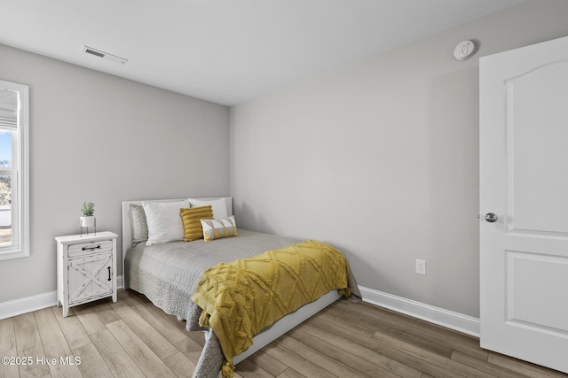 bedroom with visible vents, baseboards, and wood finished floors