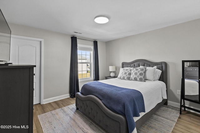 bedroom featuring visible vents, baseboards, and wood finished floors