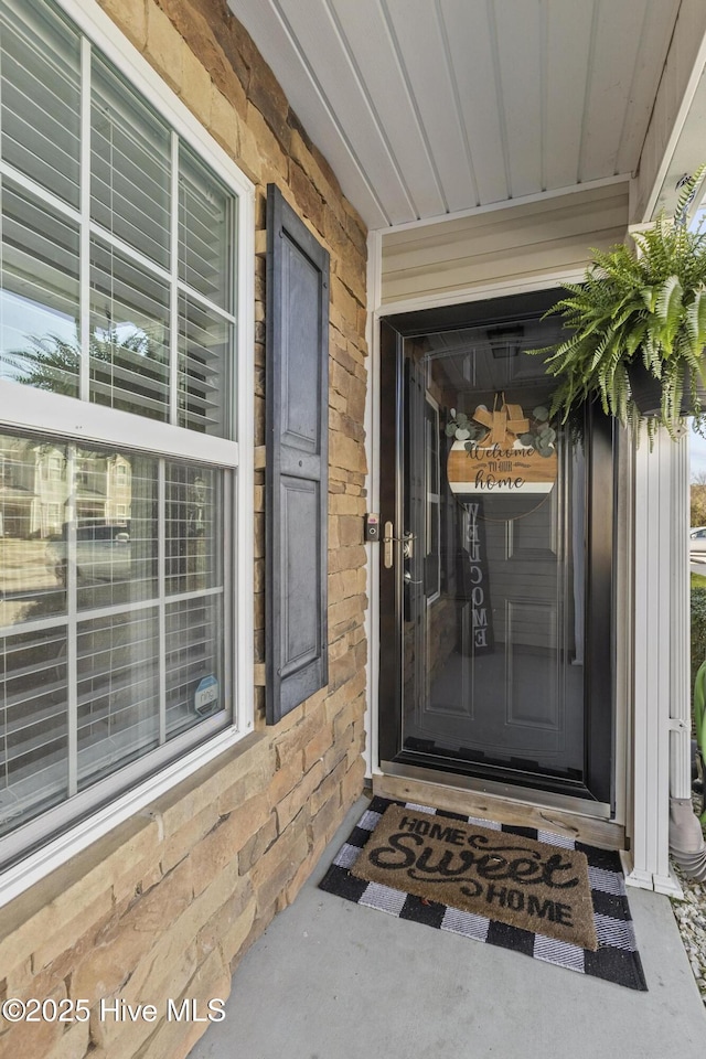 doorway to property featuring stone siding and a porch