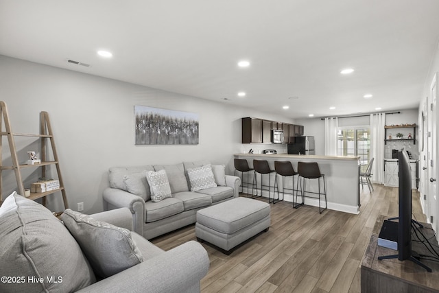 living room featuring recessed lighting, visible vents, and light wood finished floors