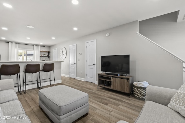 living room featuring light wood-style flooring, recessed lighting, and baseboards