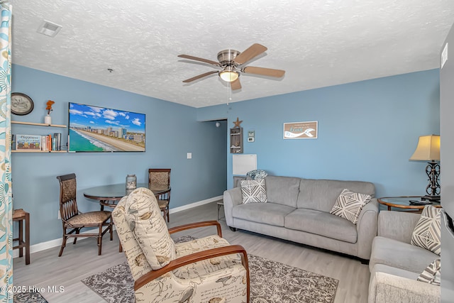 living area with baseboards, a textured ceiling, a ceiling fan, and wood finished floors