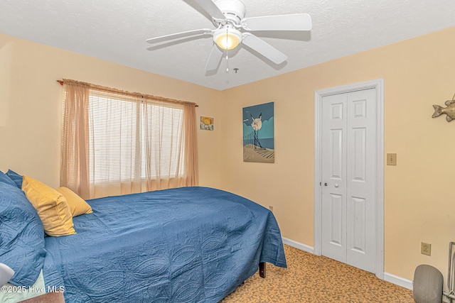 carpeted bedroom with a closet, a textured ceiling, baseboards, and a ceiling fan