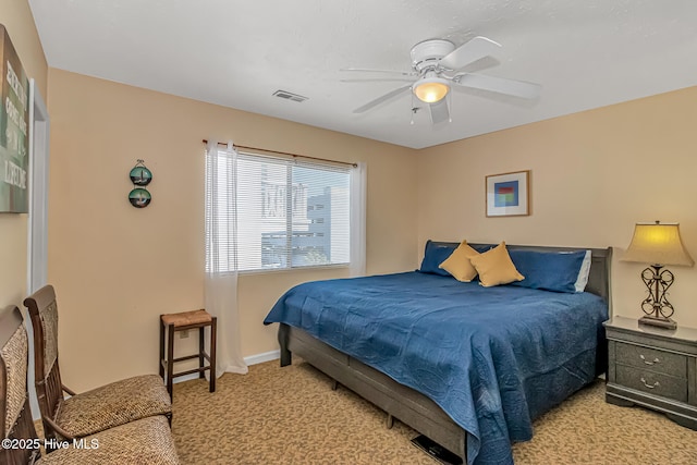 bedroom featuring baseboards, light colored carpet, visible vents, and ceiling fan