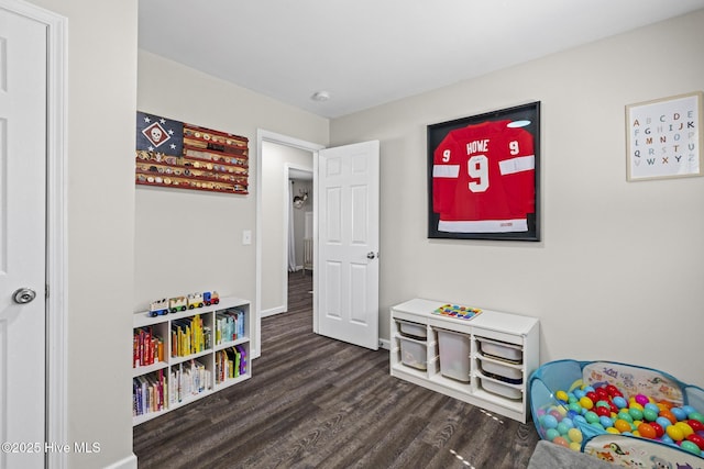 recreation room with baseboards and dark wood-type flooring