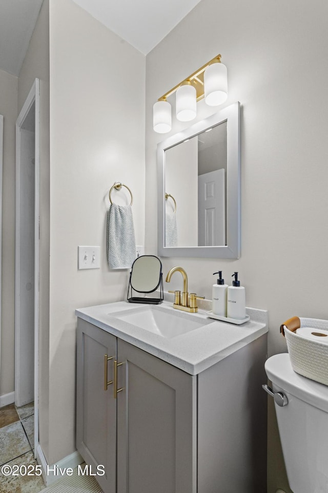 bathroom with tile patterned flooring, toilet, vanity, and baseboards