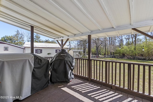 wooden deck featuring an outbuilding, grilling area, a storage unit, and a yard