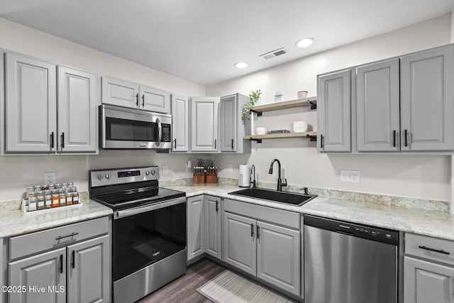 kitchen with visible vents, dark wood finished floors, gray cabinetry, a sink, and appliances with stainless steel finishes