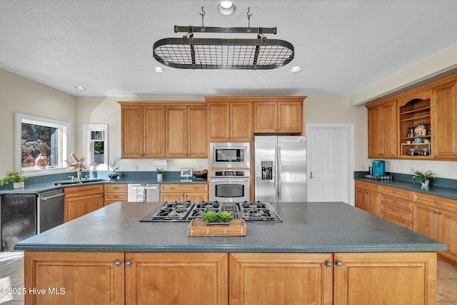 kitchen featuring recessed lighting, a sink, stainless steel appliances, dark countertops, and a center island