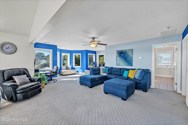 carpeted living area with visible vents, baseboards, a ceiling fan, and tile patterned flooring