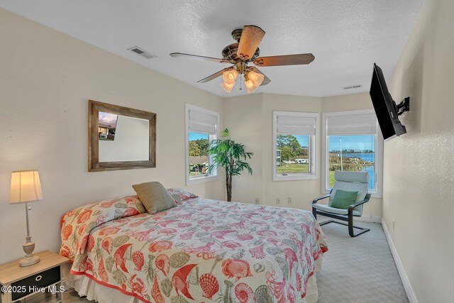 bedroom featuring visible vents, baseboards, carpet floors, a textured ceiling, and a ceiling fan