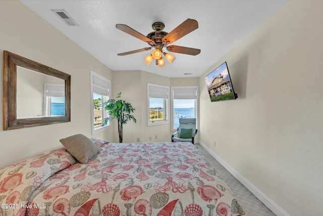 carpeted bedroom with multiple windows, baseboards, visible vents, and ceiling fan