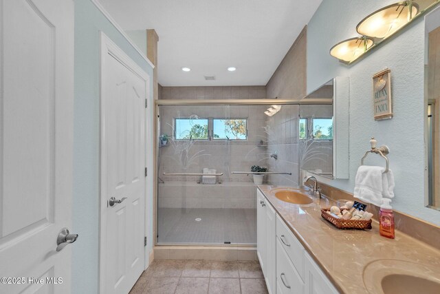 full bathroom featuring tile patterned flooring, a shower stall, double vanity, and a sink