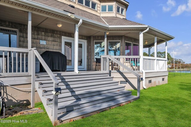 wooden deck featuring covered porch, a lawn, and a grill