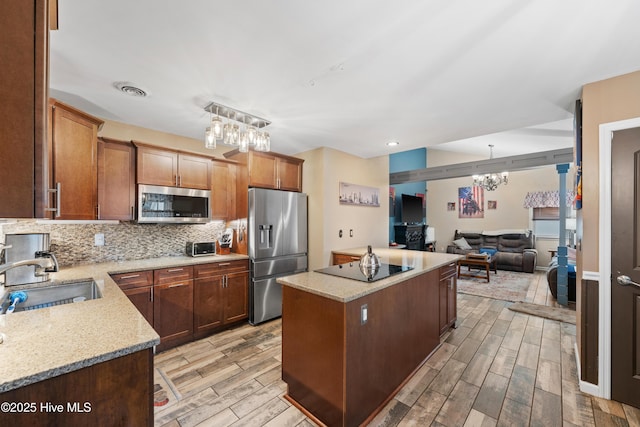 kitchen with a notable chandelier, a sink, a center island, stainless steel appliances, and wood tiled floor