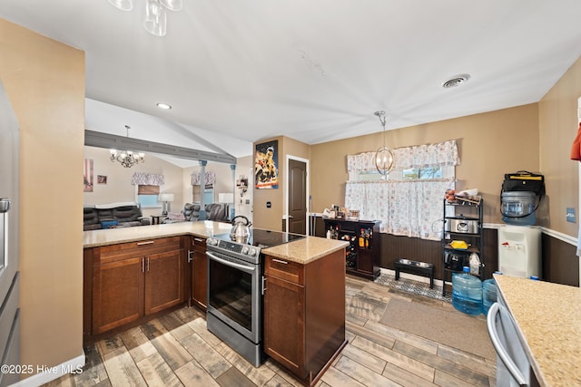 kitchen with wood tiled floor, electric stove, pendant lighting, open floor plan, and a chandelier