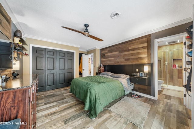 bedroom with ornamental molding, visible vents, wood walls, and light wood-type flooring