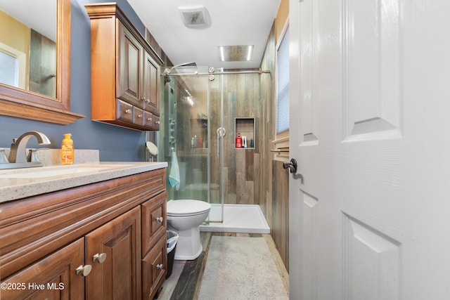 bathroom featuring toilet, a shower stall, and vanity