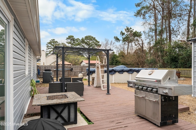 deck featuring a grill, a fire pit, a fenced backyard, and a pergola