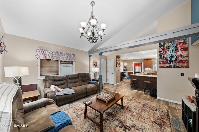 living area with vaulted ceiling, baseboards, light wood-type flooring, and a chandelier