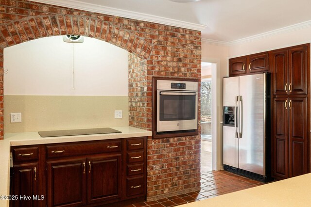 kitchen featuring appliances with stainless steel finishes, light countertops, dark tile patterned flooring, and ornamental molding